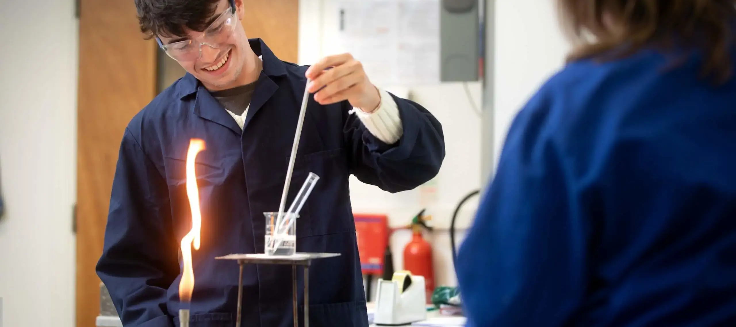 Pocklington School Sixth Former and teacher in Chemistry lab with lit bunsen burner and beaker