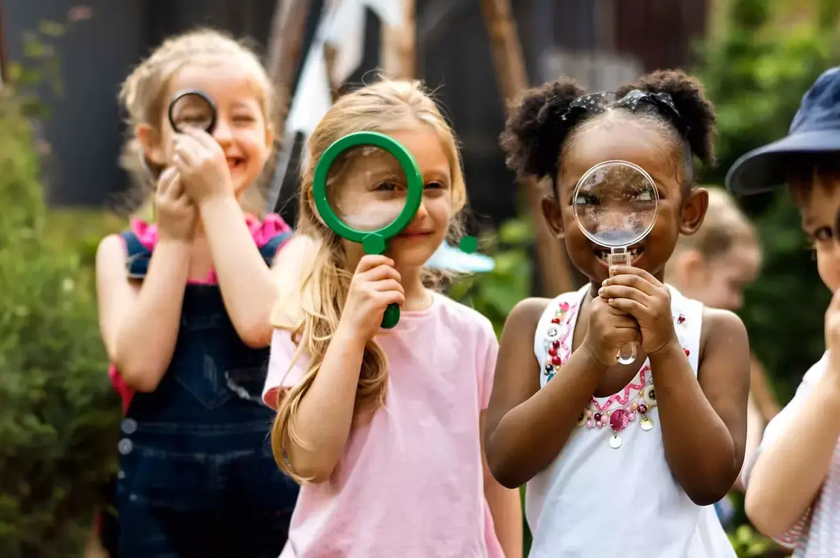 Nursery pupils playing with magnifying glasses