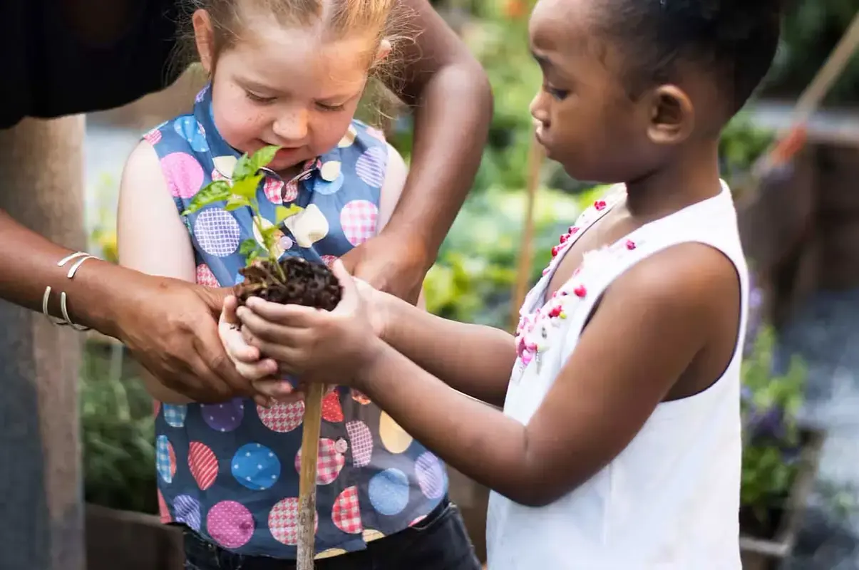 Nursery pupil with teacher in the garden planting a plant at Pocklington School