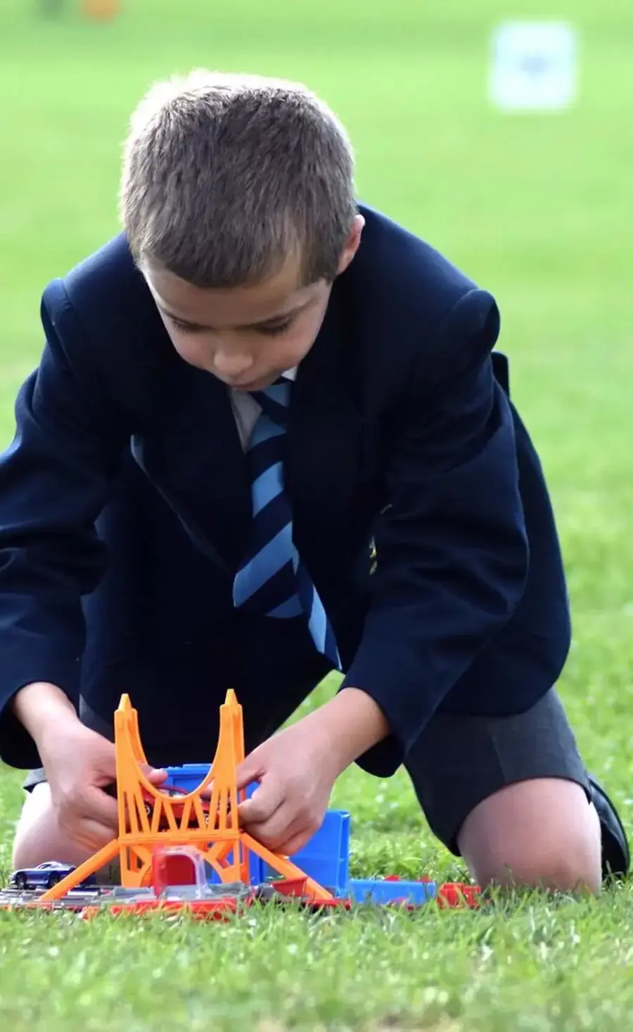 Pocklington Prep School pupil sitting on the grass and playing with some toys 