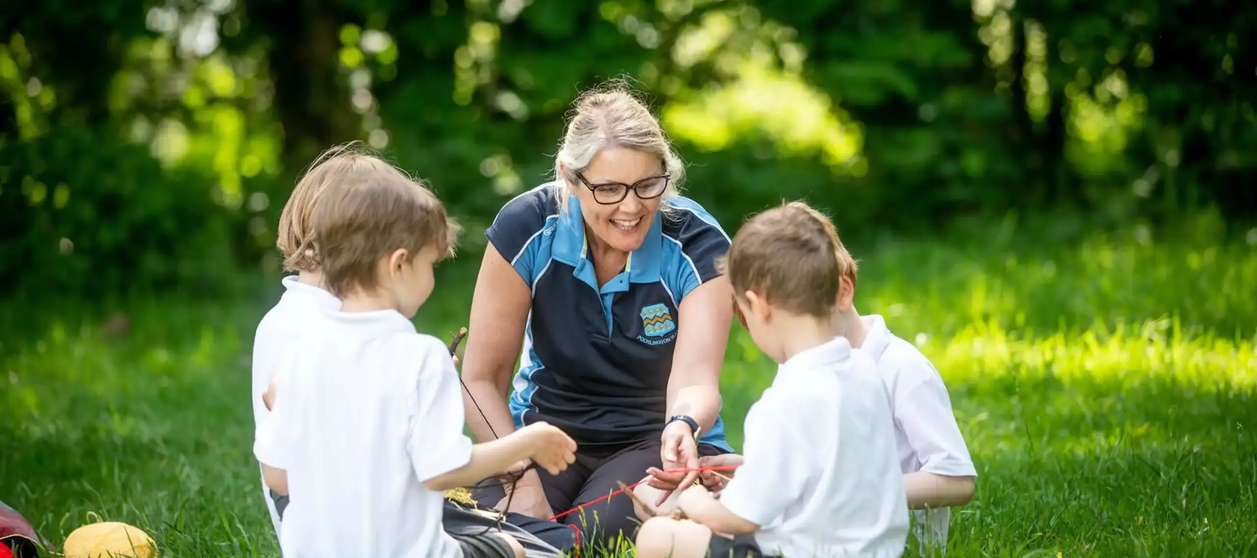 Teacher sits outside teaching forest school to four Pocklington School pupils 