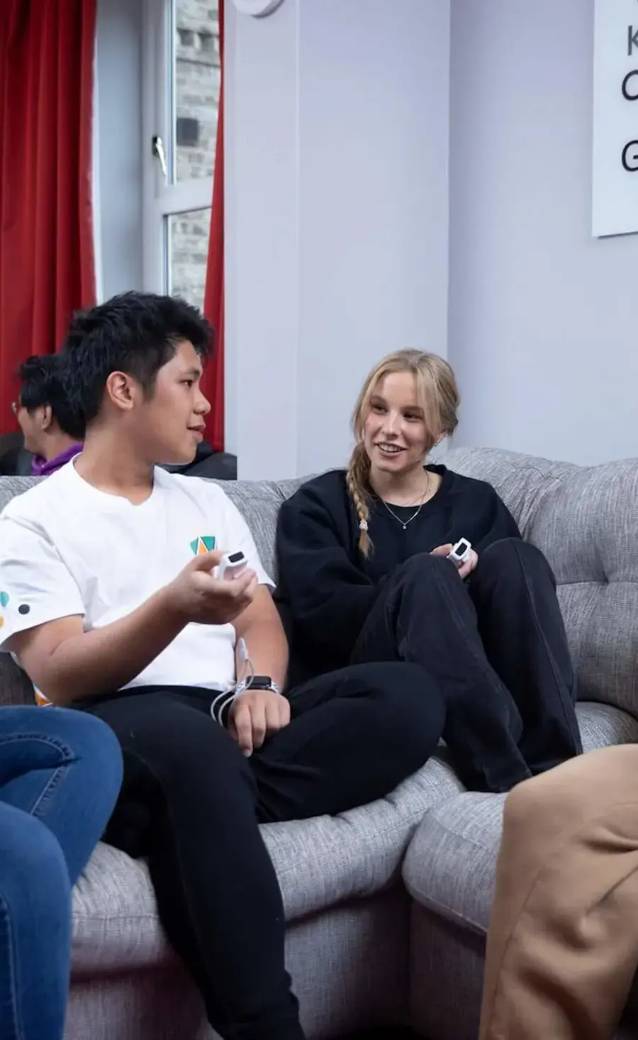 Four Pocklington School boarders sitting on a sofa in a boarding house, laughing together