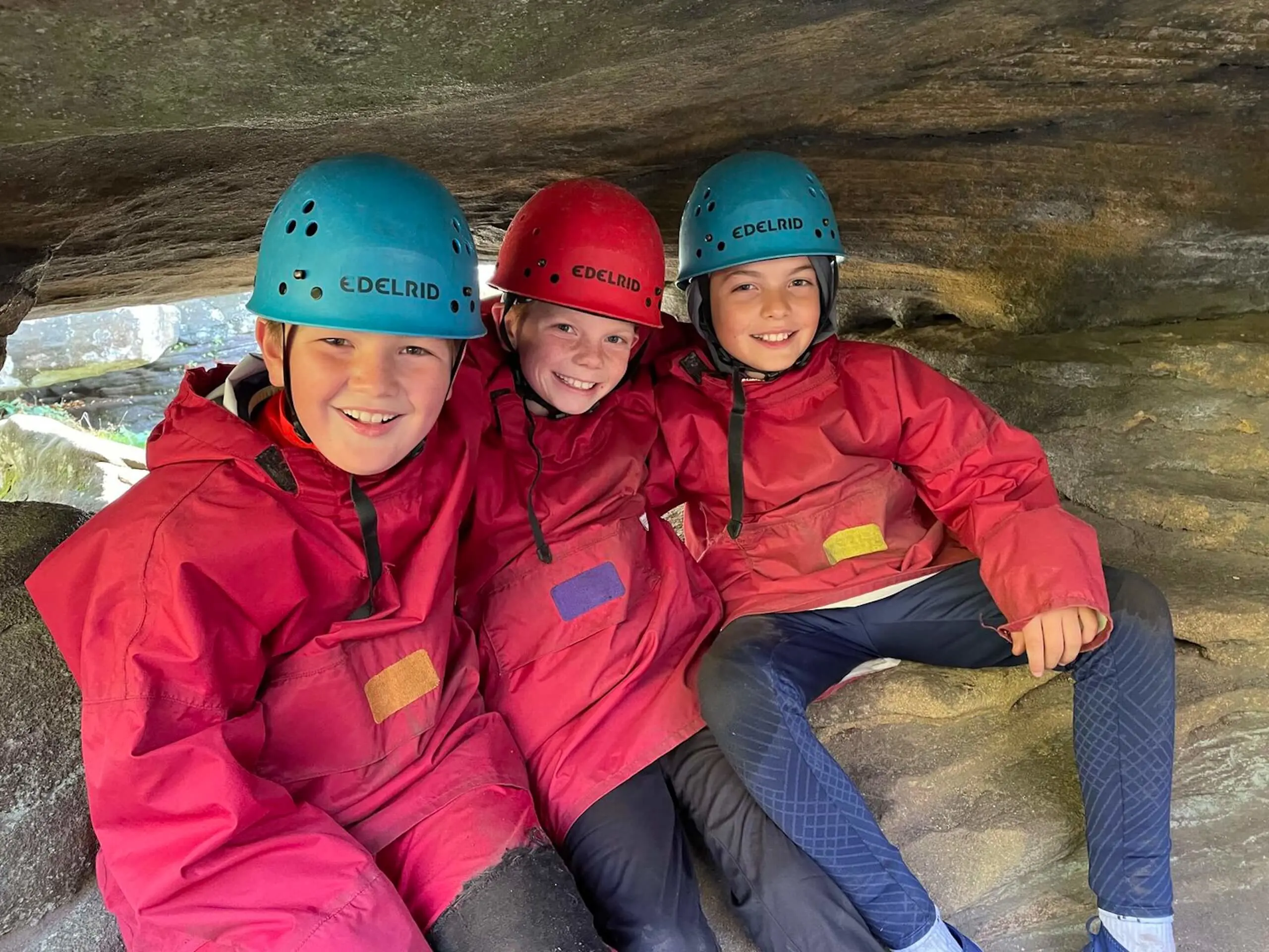 Three Pocklington Prep School pupils smiling in a cave on a residential trip 