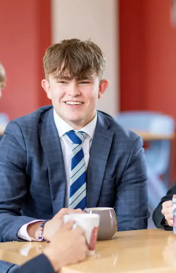 Pocklington School Sixth Former chatting to friends with a mug in Sixth Form cafe