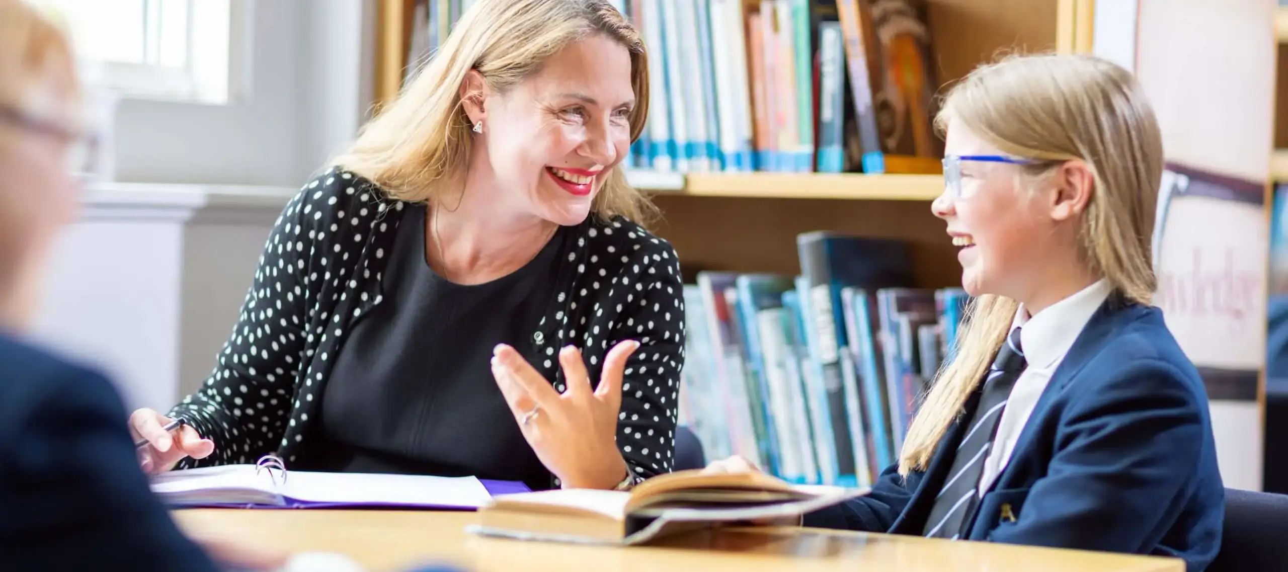 Teacher and pupil in library talking and laughing