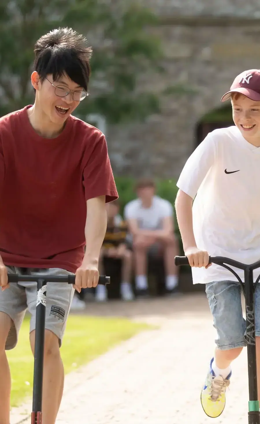 Two Boarding pupils on scooters outside boarding house