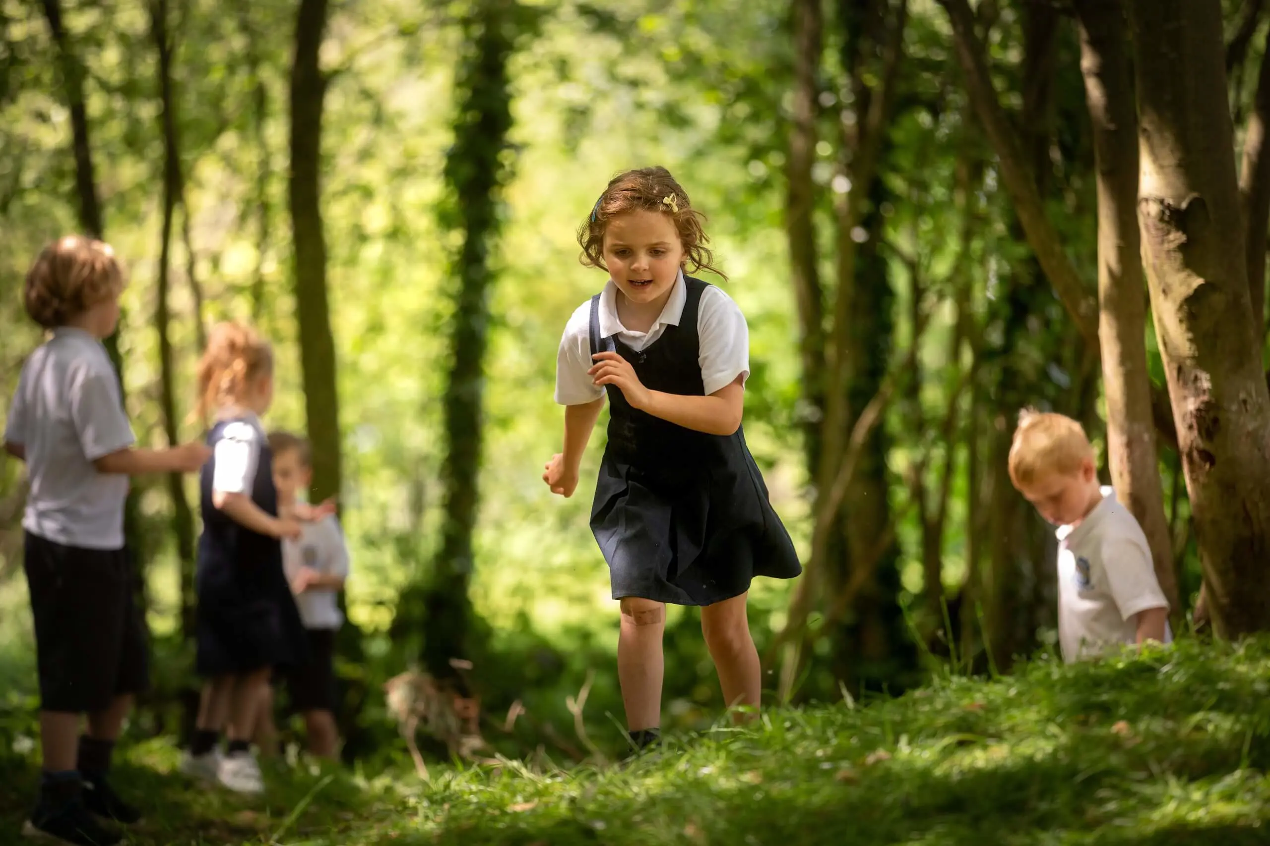 Pocklington Pre Prep pupil running joyfully through the forest, surrounded by friends. 