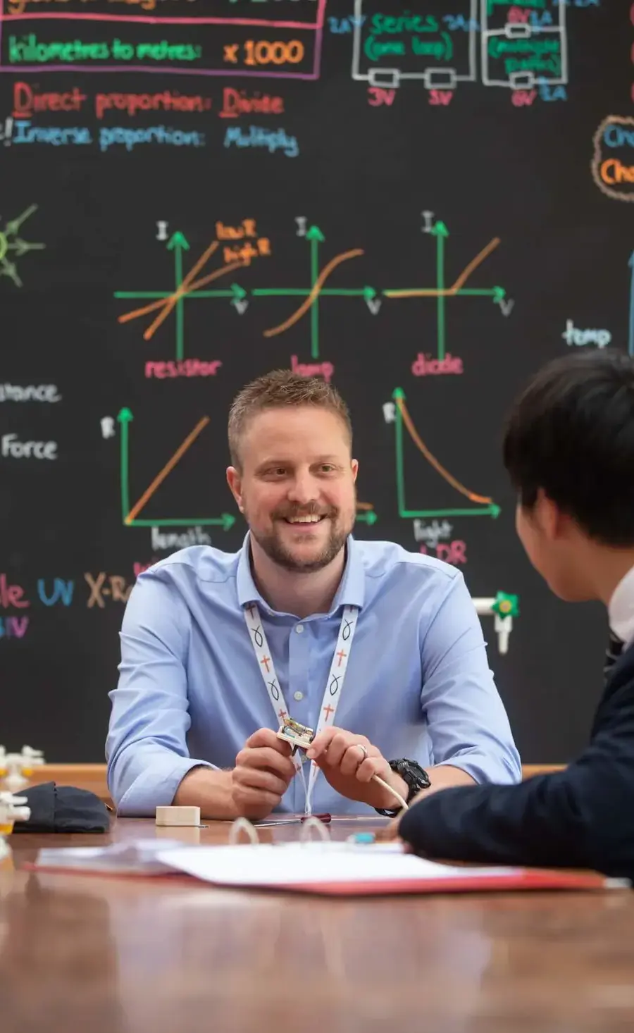 Physics teacher and pupil sat at a classroom bench talking in the Pocklington School physics laboratory