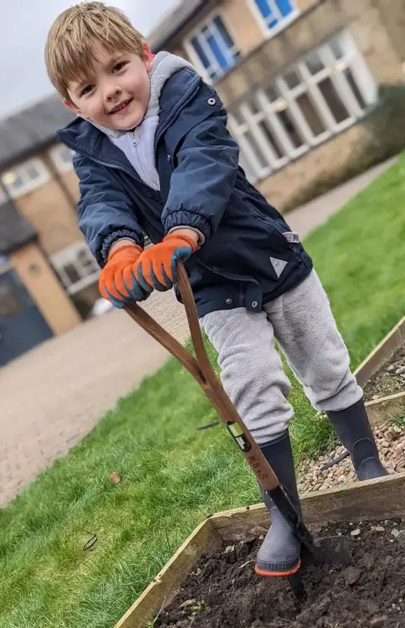 Pocklington Pre-Prep pupil outside with spade gardening