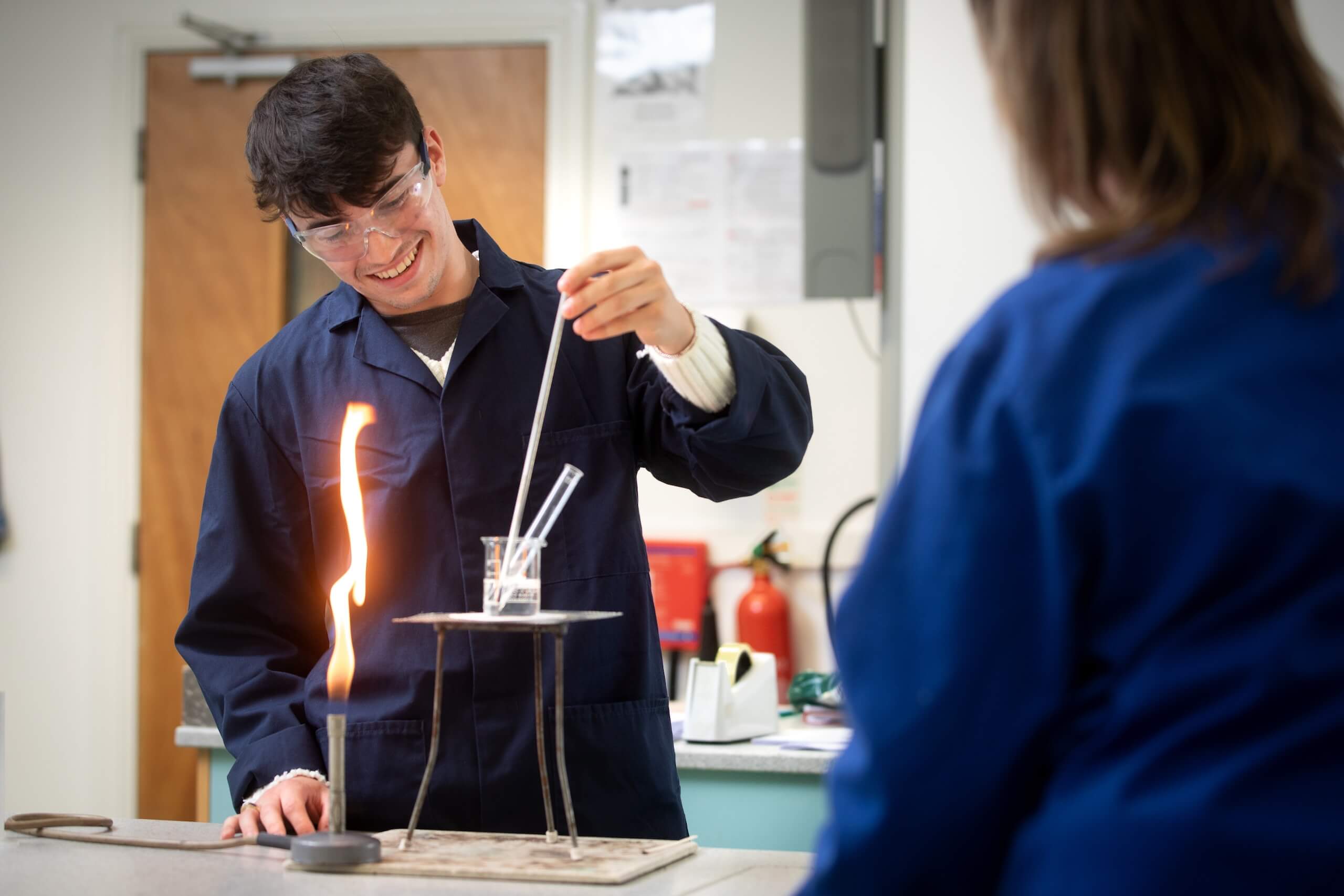 Pocklington School Sixth Former and teacher in Chemistry lab with lit bunsen burner and beaker