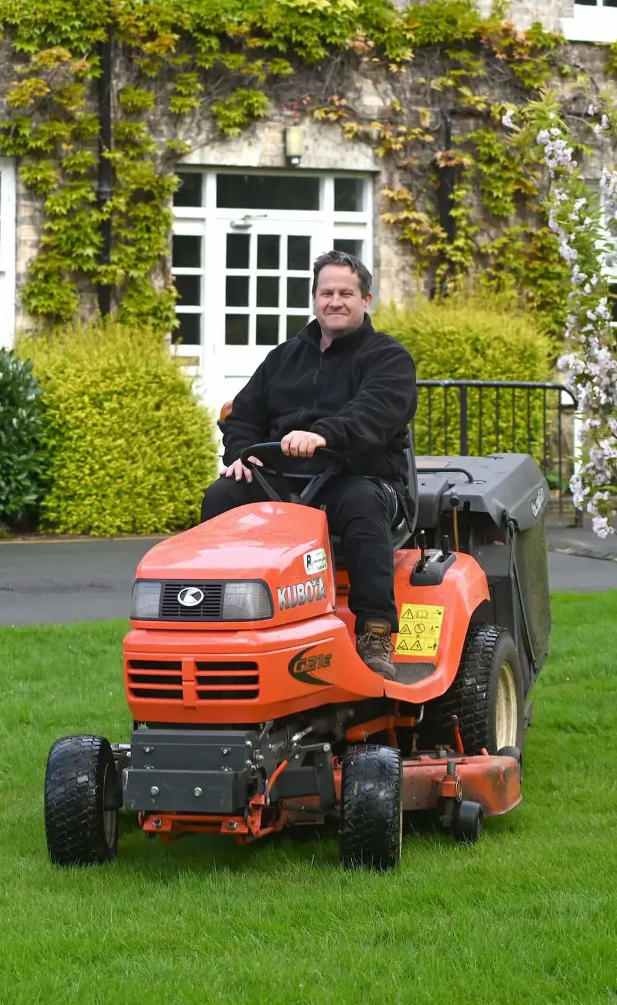 Pocklington School gardener mowing on a sit on lawnmower outside Pocklington School