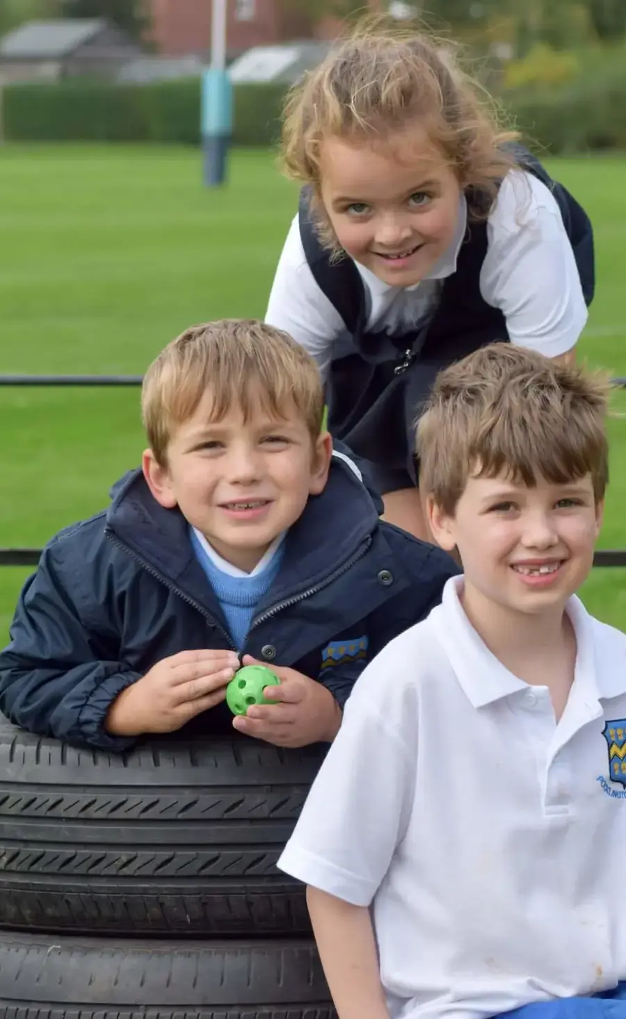 Three Pocklington Early Years pupils outside playing at breaktime