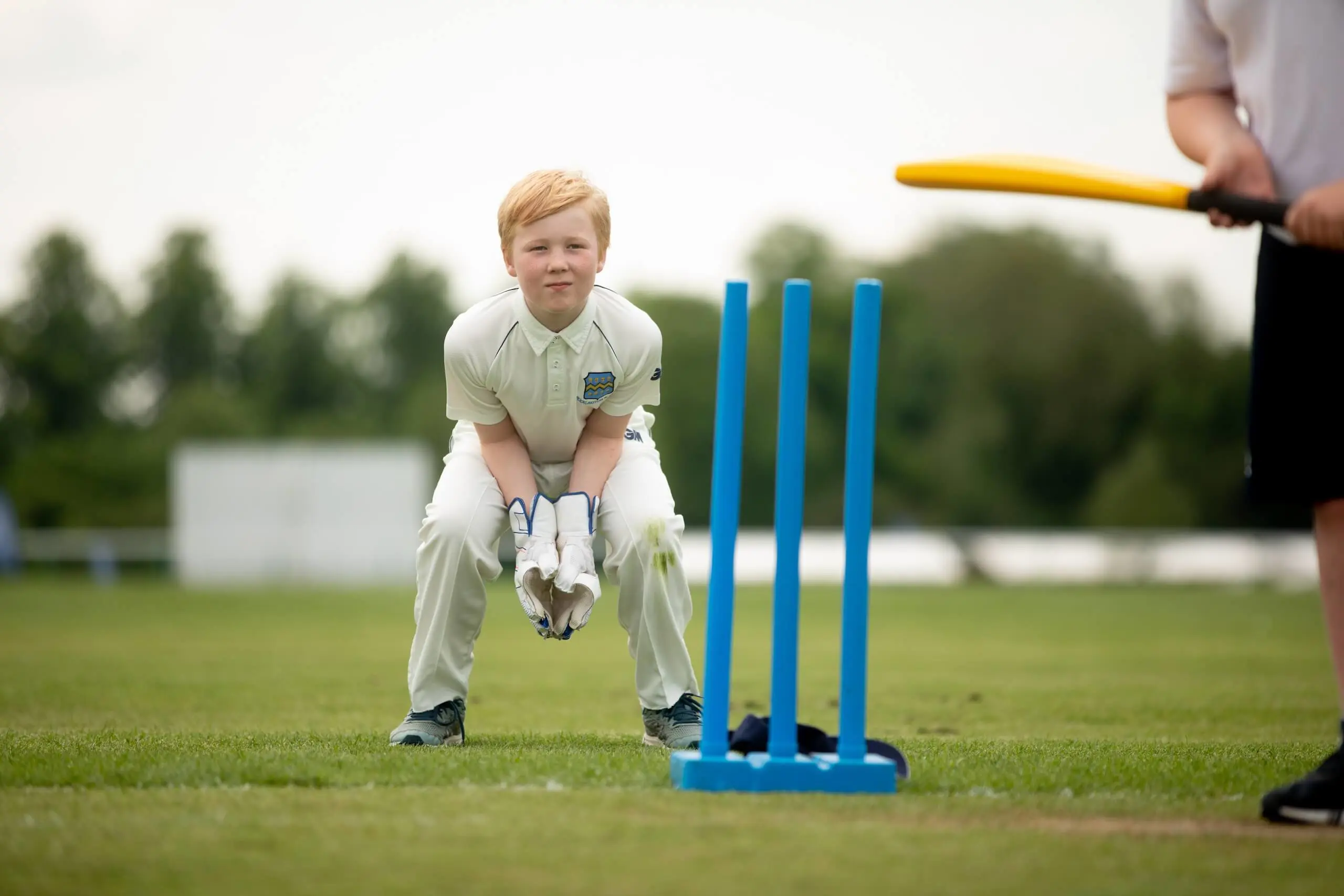 Pocklington School pupil in cricket whites standing behind wickets about to catch cricket ball